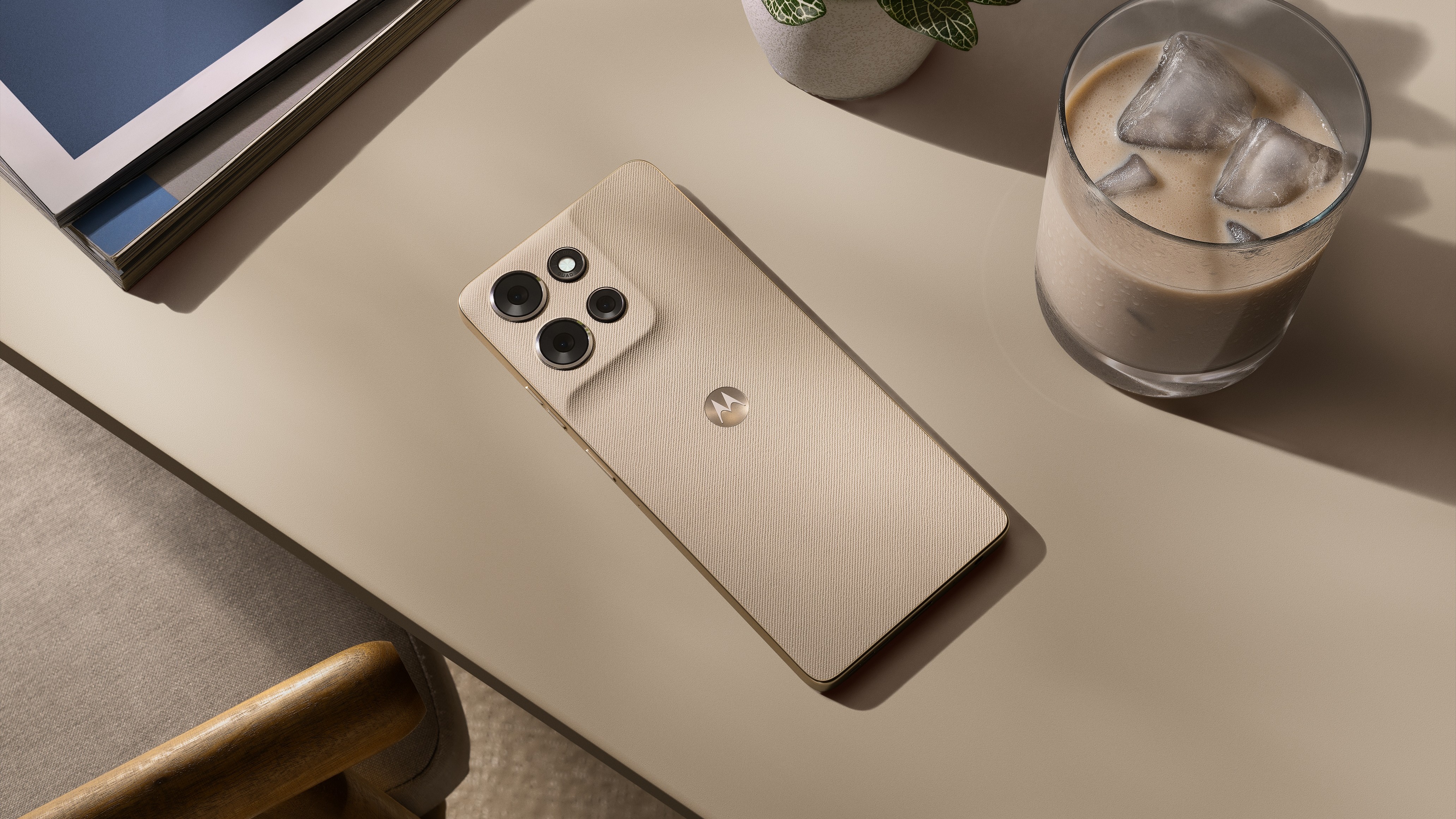 Motorola G Power 2026 in a Cashmere color beside an iced coffee on a cream-colored table.