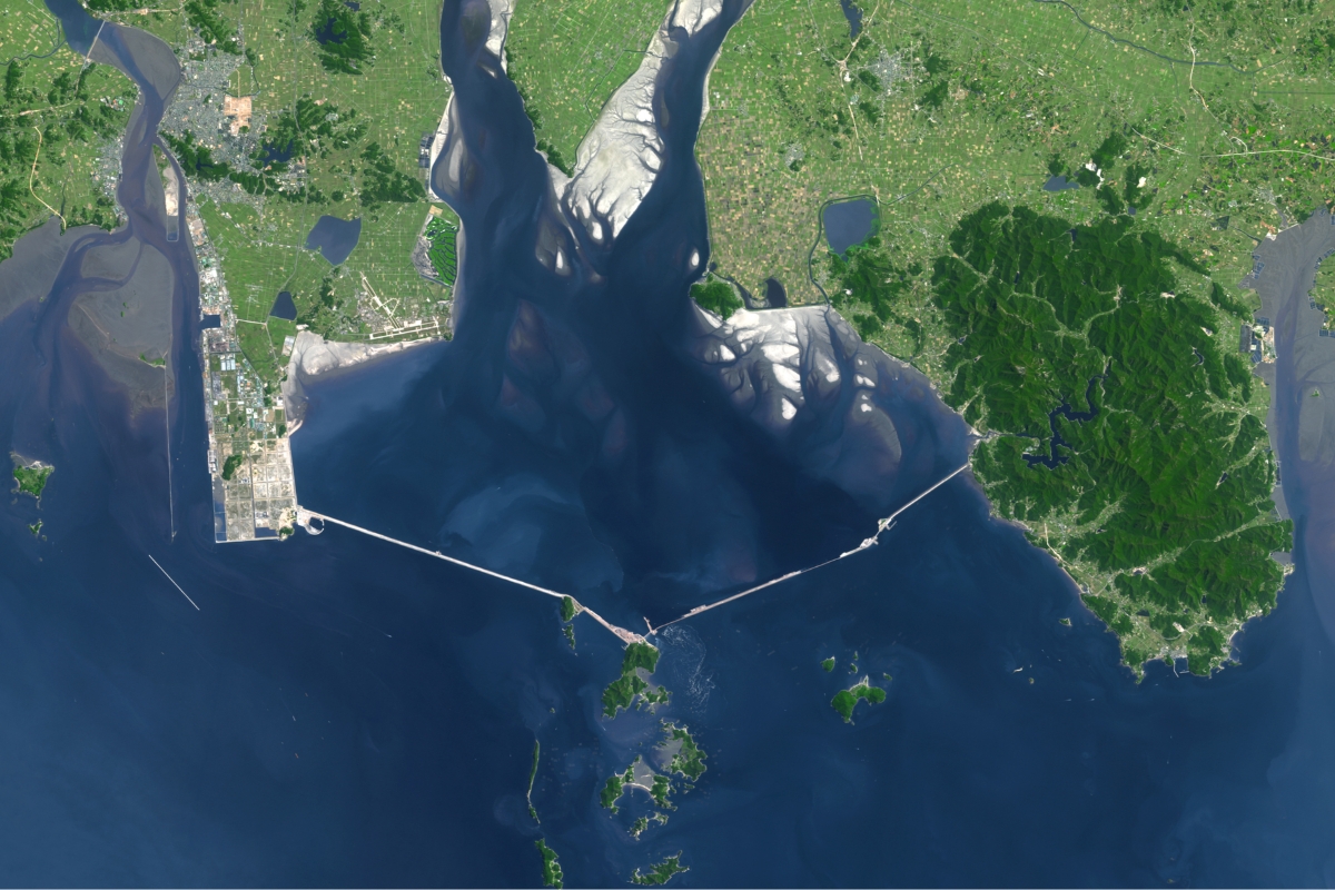 Visible from space, a 33 km structure, considered the world's largest sea wall, closed off an entire bay, created artificial land, and placed economic development and environmental preservation on opposite sides