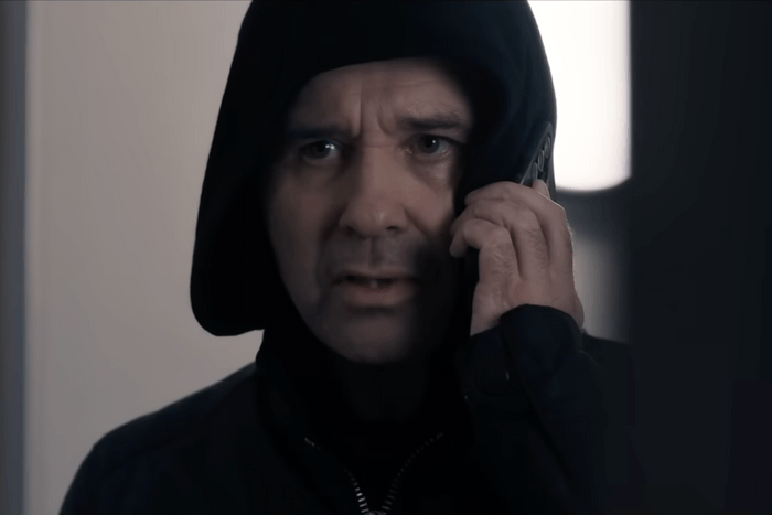 Andrew Scarborough as Graham Foster in a black hoodie and on the phone in Corriedale.