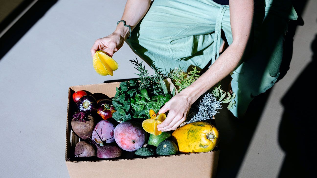Person sorting through a box of vegetables