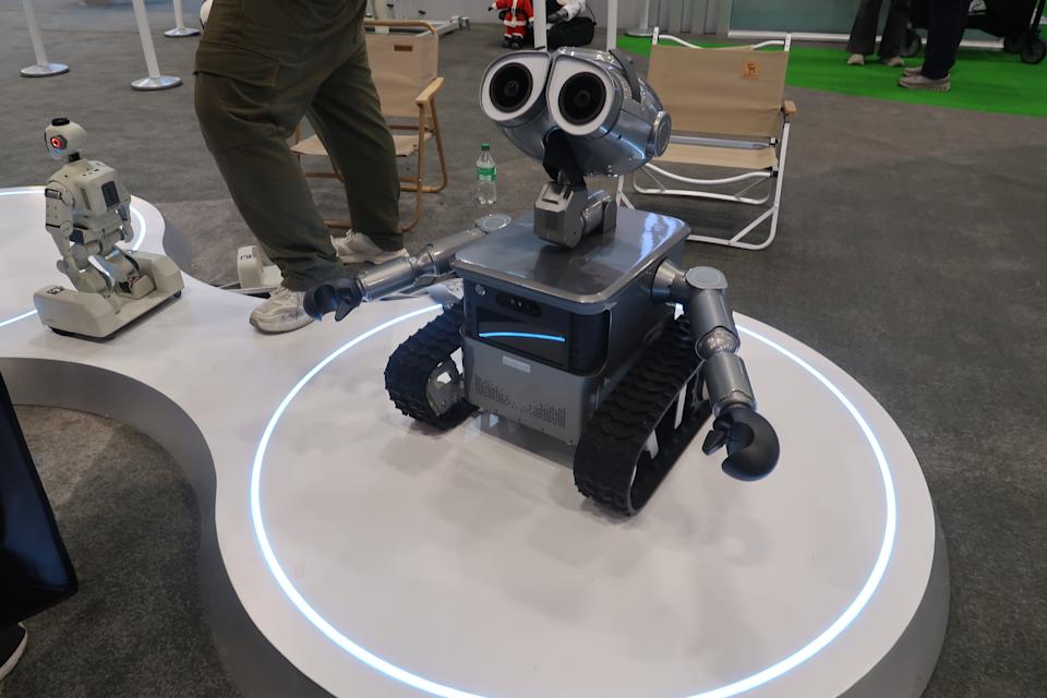 Zeroth's robot that resembles Wall-E is pictured standing on a circular platform, with its arms held out to its side and looking slightly up