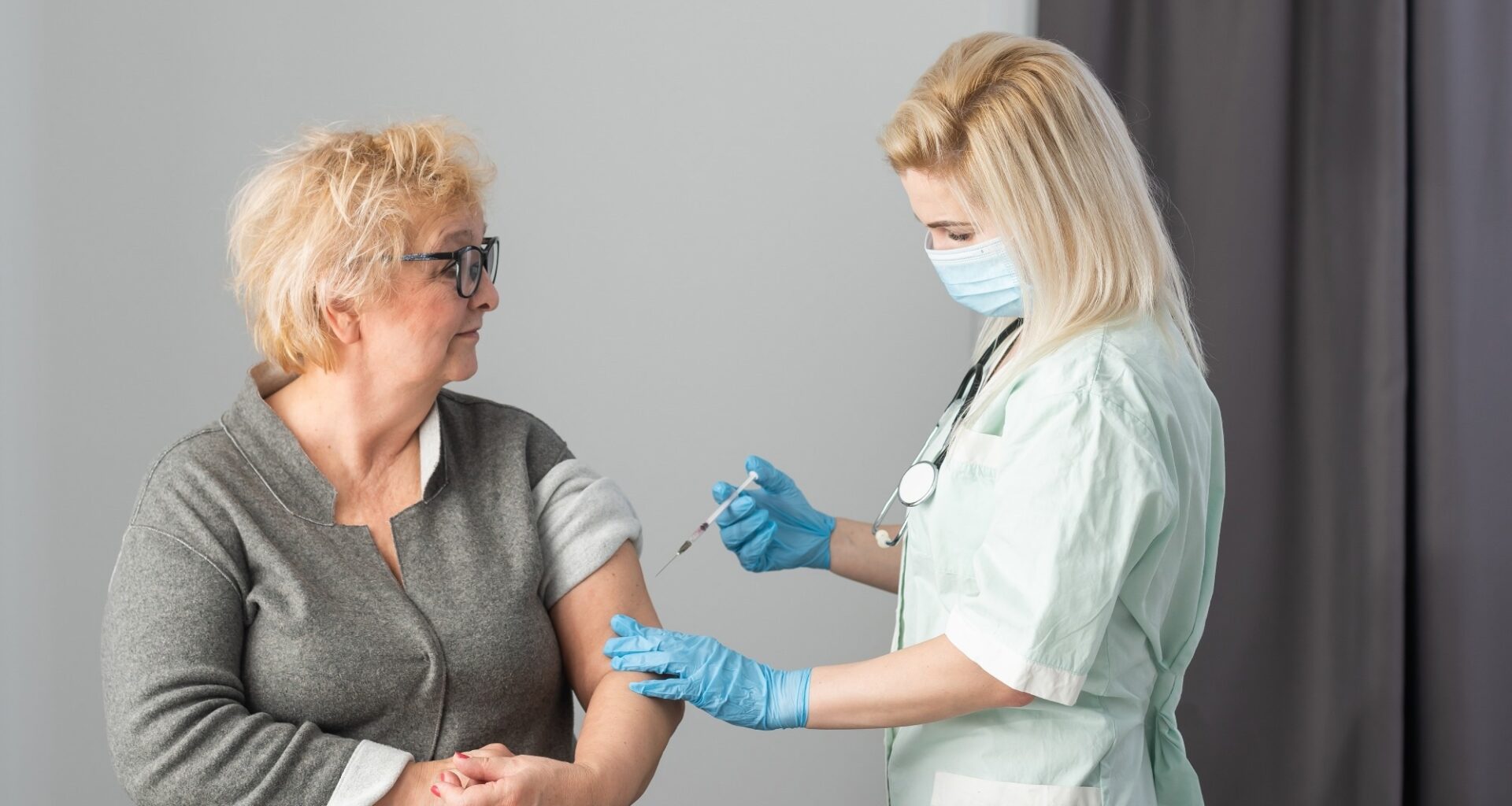 Older adult getting immune vaccine in arm for flu shot in hospital by nurse.