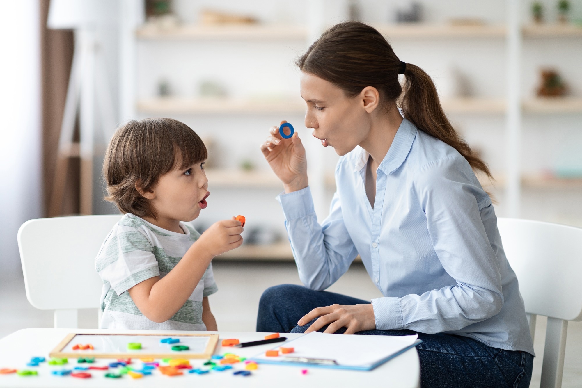 Little boy learning letter O with private English language tutor during lesson at office