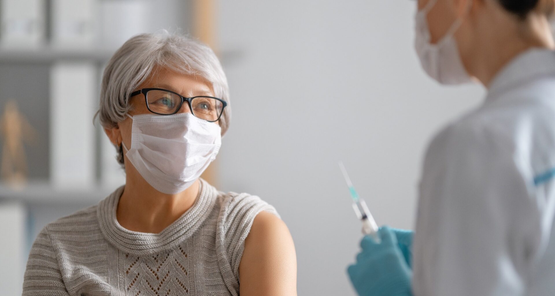 Doctor giving a senior woman a vaccination.