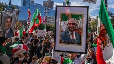 An unidentified man holds a picture of Reza Pahlavi while members of the Iranian community and supporters hold signs and pre-regime Iranian flags during a "Solidarity with the People of Iran" event in front of City Hall in Downtown (Getty Images via AFP)