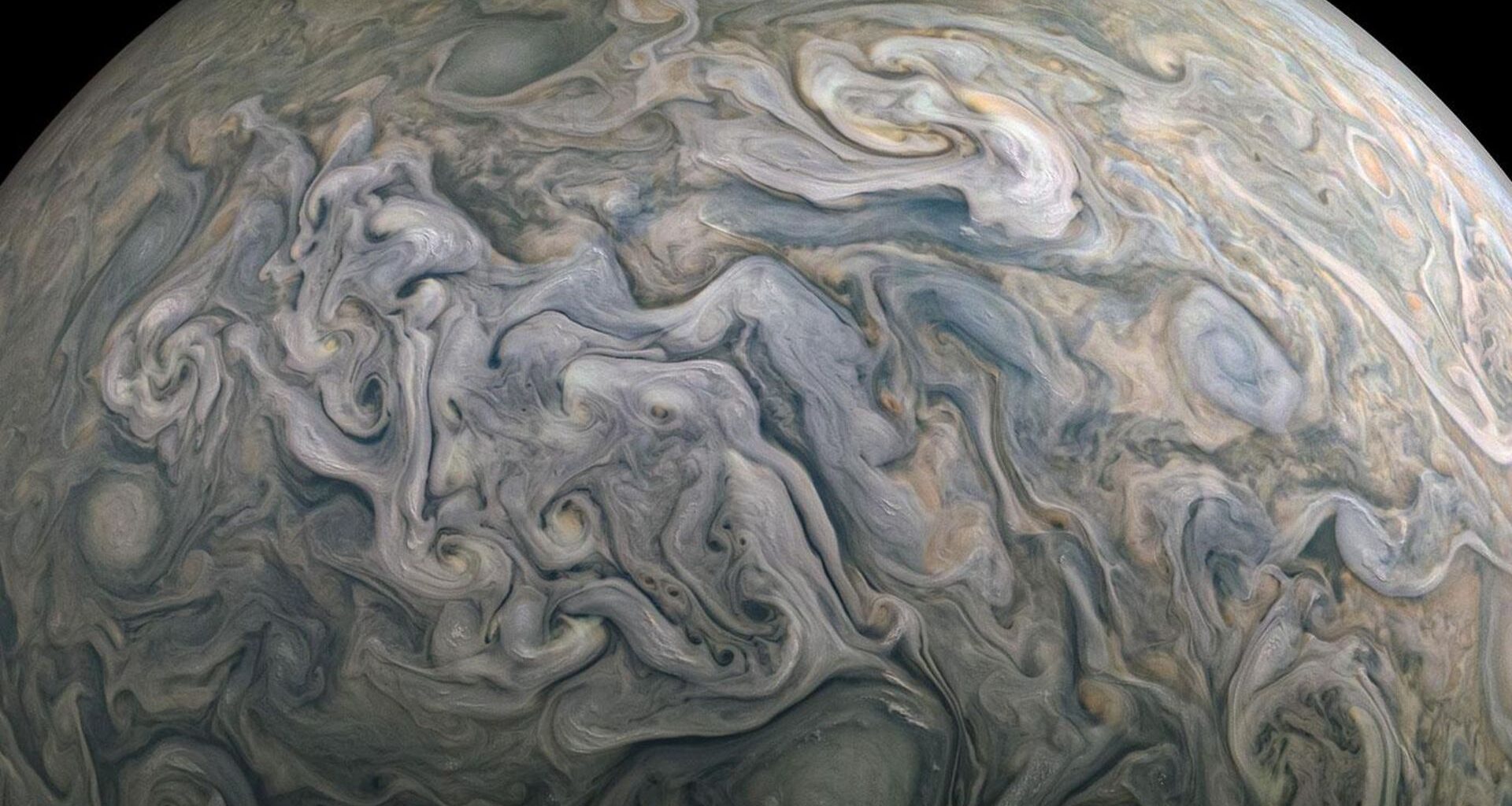 A close up of Jupiter's surface in space where clouds of blue and gray swirl.