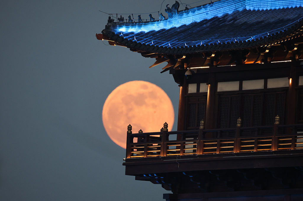 The Wolf Moon hangs in the sky behind a building in China.