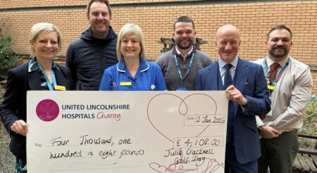Six people stand behind a giant cheque