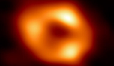 Black hole: Fuzzy glowing yellow and orange donut with black center and 3 brighter spots along the ring.