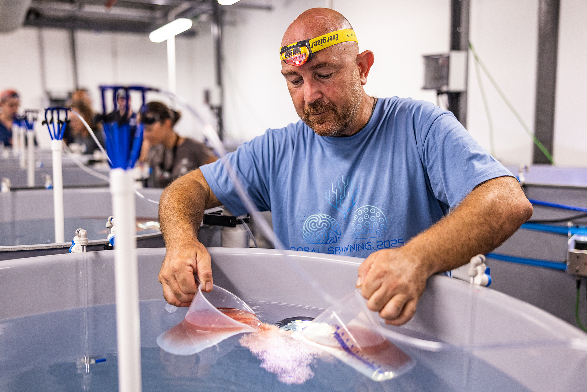 A man holding two measuring cups in a tank of water