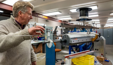 A scientist looks over a complex winding tool used to create magnets.