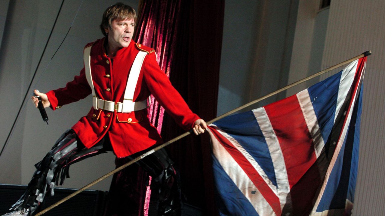 Bruce Dickinson of Iron Maiden holding a union flag and wearing Crimean War uniform onstage in 2005