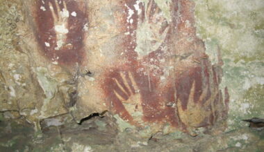 photo of pointy-fingered hand stencils on a cave wall