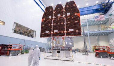 A pair of scientists stand in front of the fully completed Roman space telescope