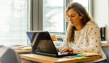 Student engaged in online learning using a laptop in a bright, modern workspace