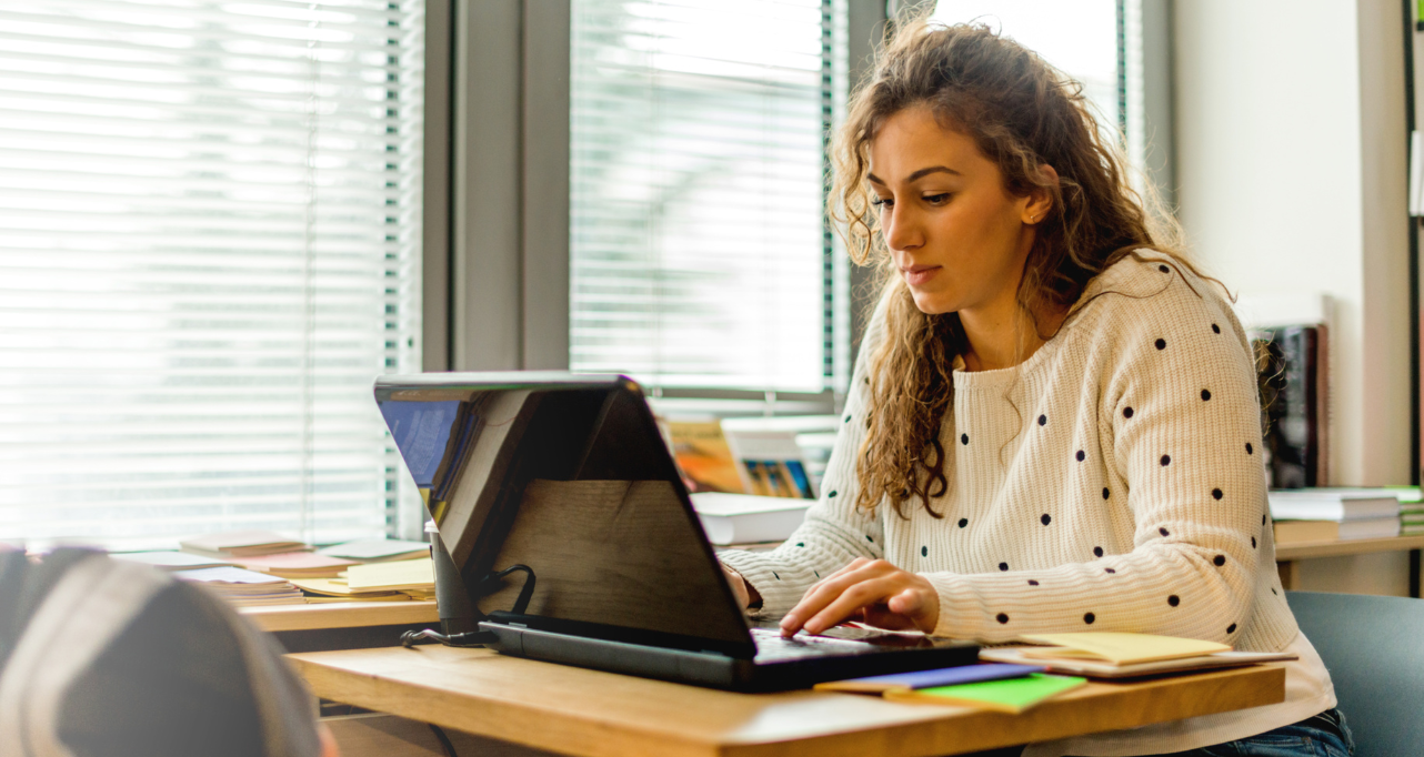 Student engaged in online learning using a laptop in a bright, modern workspace