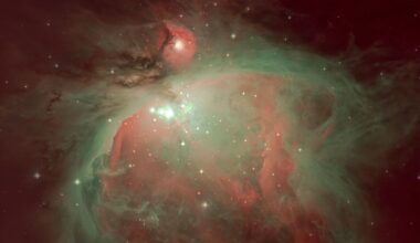The swirling mass of interstellar dust and gas that forms the Orion Nebula is pictured glowing against the blackness of space. A collection of particularly bright stars are visible in the center of the nebula, surrounded by a radiation-sculpted cavity.