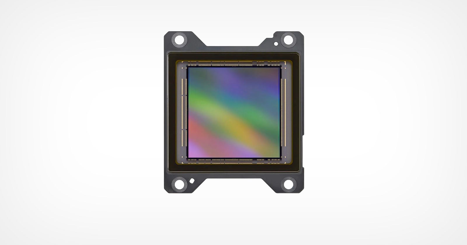 A close-up image of an electronic sensor, likely a camera sensor, with a rainbow-colored reflective surface and four mounting holes, set against a plain white background.