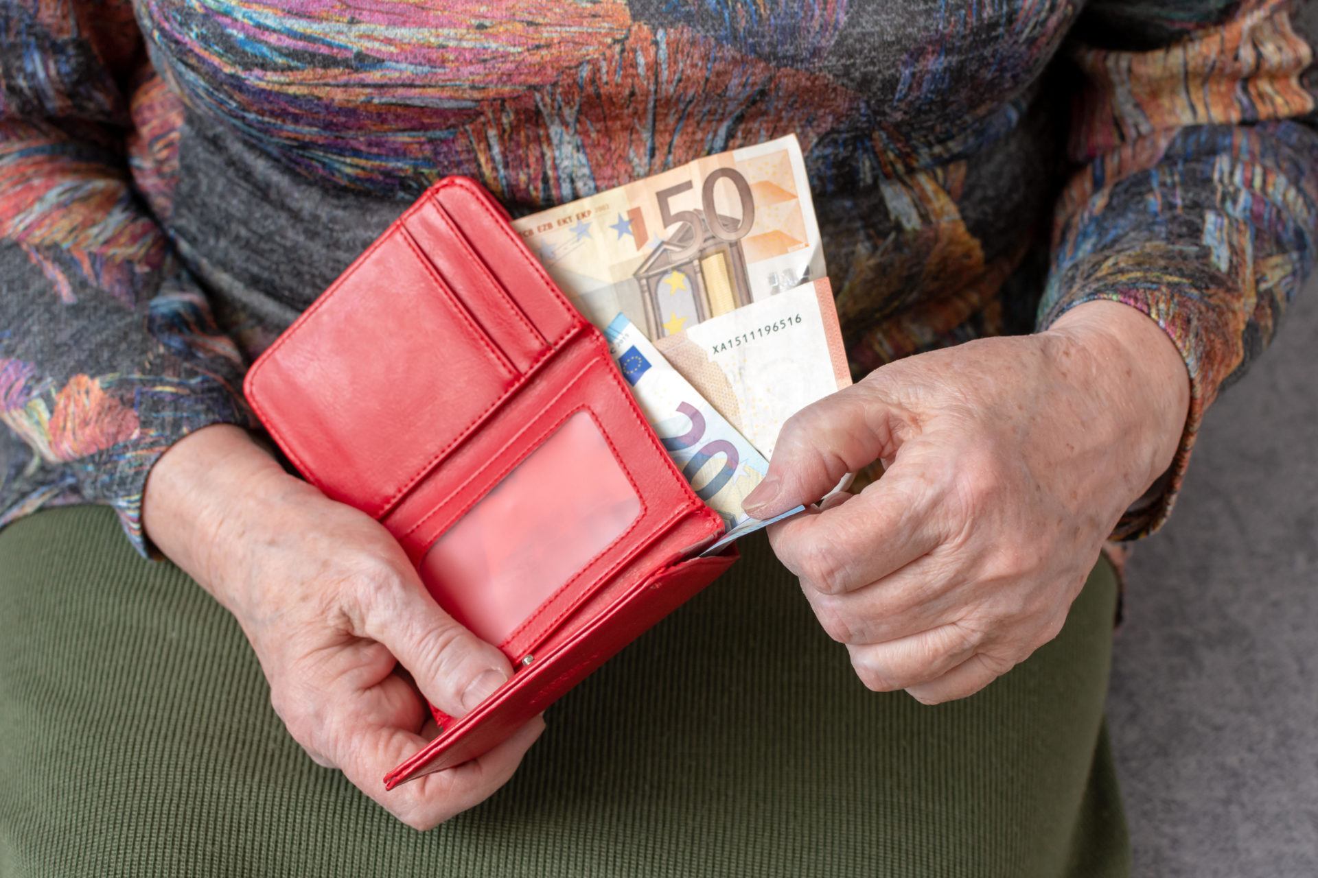 T05ACC Hands of an elderly pensioner holding leather wallet with euro currency money. Concept of financial security in old age.
