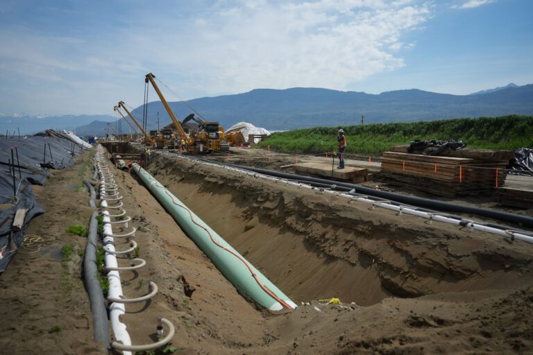 Workers position pipe during construction of the Trans Mountain pipeline expansion in Abbotsford, B.C., in May 2023.