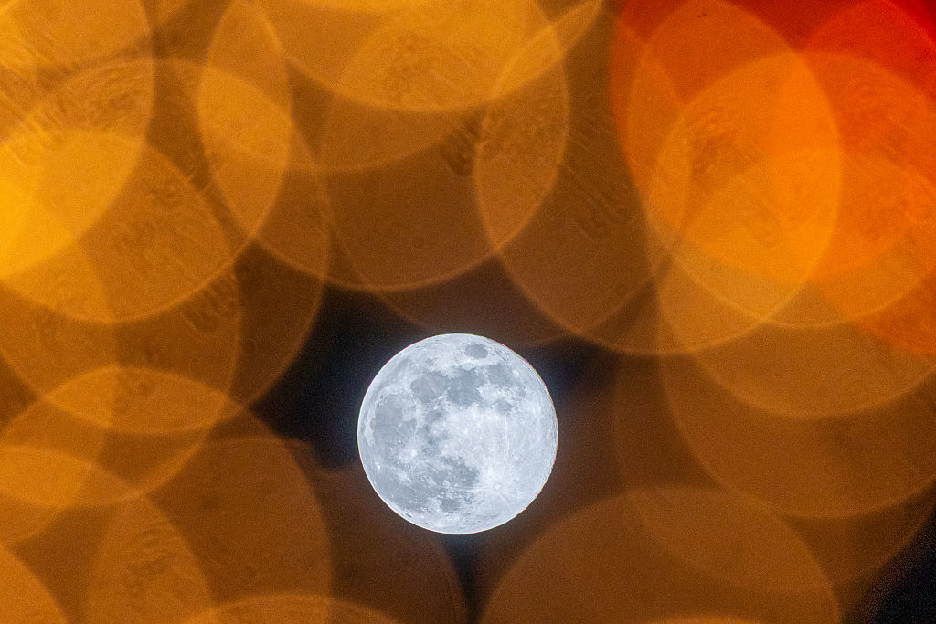 Wolf Moon seen behind blurry Christmas lights.