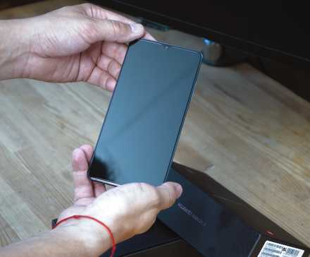 A man holding an Android phone trying to power it on