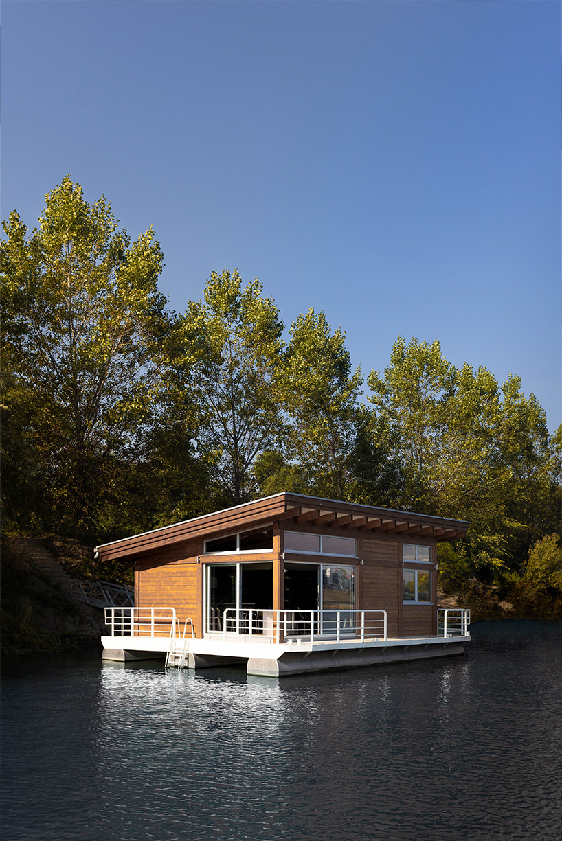 mono-pitch roof shields compact wooden cabin floating along river in serbia