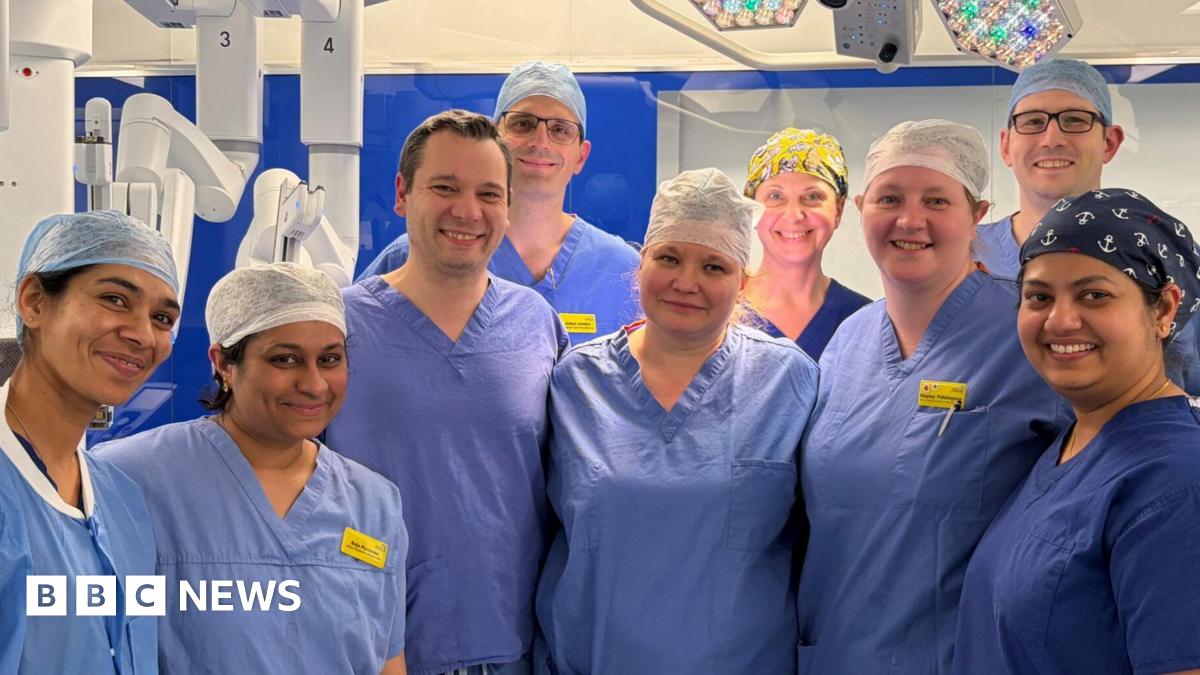 Donald Trump and Keir Starmer sit in a formal drawing room setting  on arm chairs with US and UK  flags behind them. Both have serious expressions and are looking out and not at each other.