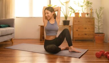 woman sits on yoga mat doing a triceps stretch