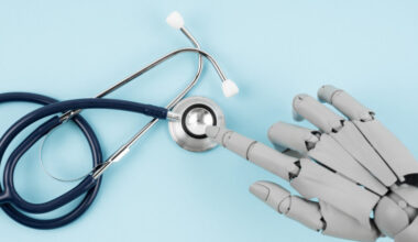 Robot hand toy finger and medical stethoscope on blue background, AI and smart technologies in medicine and diagnostic concept