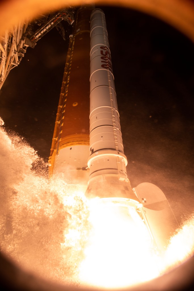 Viewed from ground level, NASA's SLS rocket lifts off as a bright fireball streams from the bottom of the rocket.