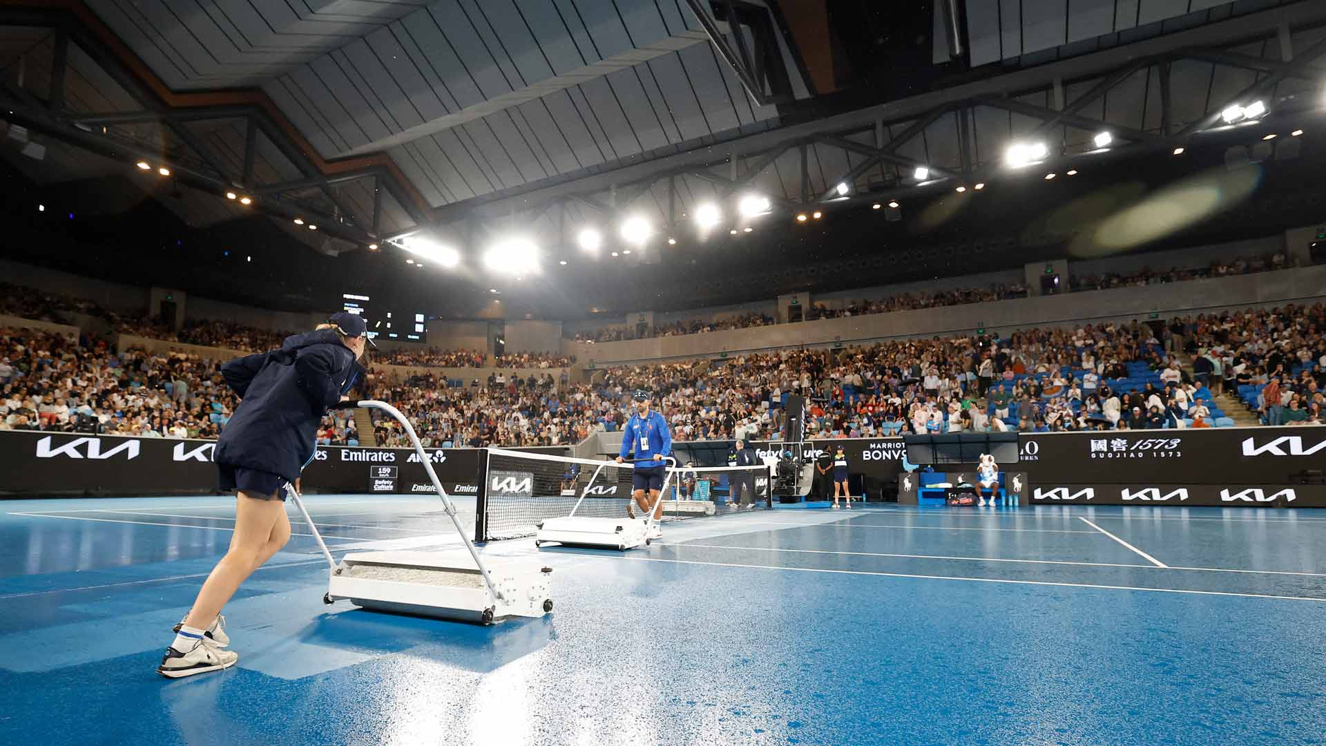 Ball kids dry a court at the Australian Open on Wednesday evening.