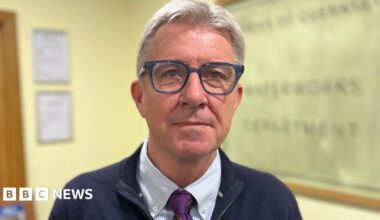 Deputy Mark Helyar - A man with grey hair, wearing blue spectacles. He has a blue jacket on with a blue and white checked shirt.