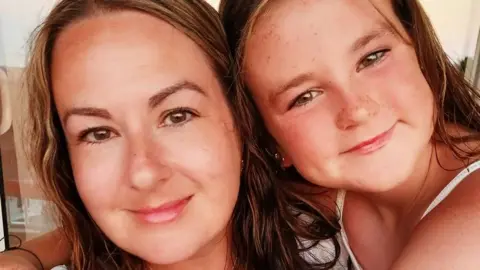 Family photo Close up headshots of Kayleigh and her daughter Skylar. Both are white with light brown hair and Kayleigh's has highlight streaks. They are both lightly tanned and and are smiling at the camera.