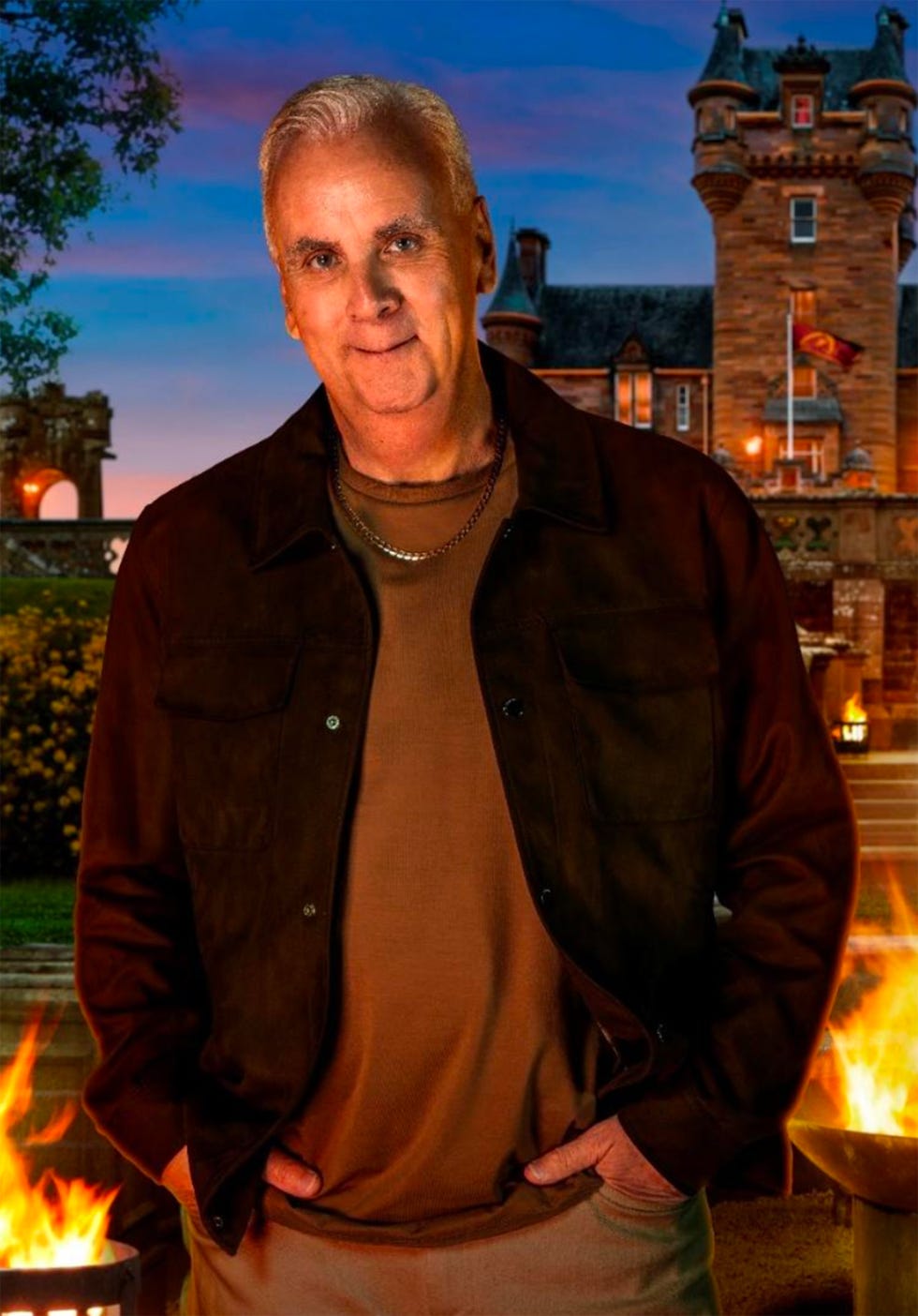 a man stands in front of a castlelike structure with fire glowing nearby