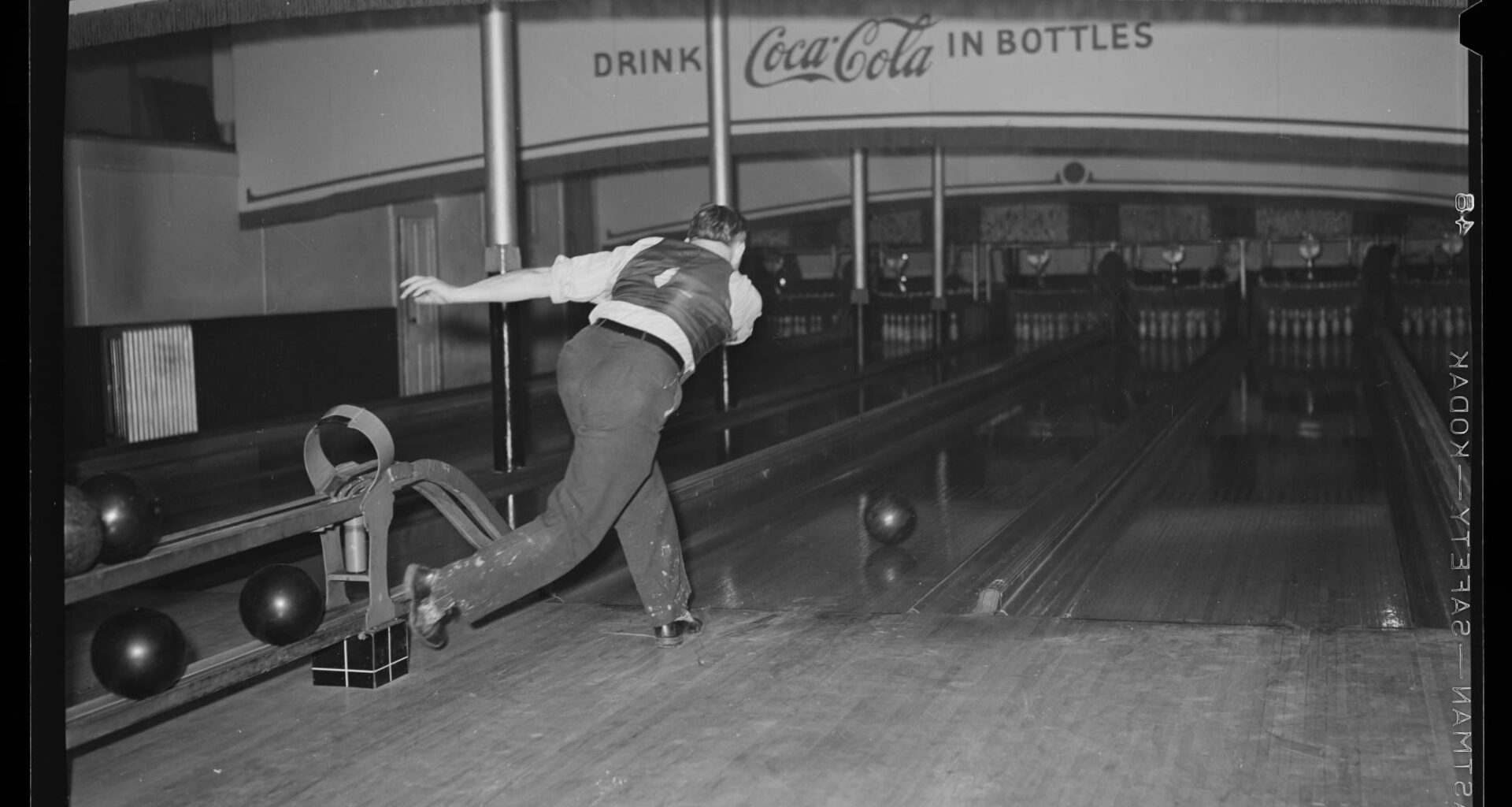 a black and white photo of a man bowling by himself