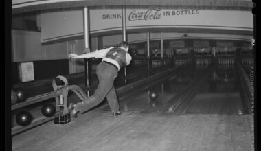 a black and white photo of a man bowling by himself