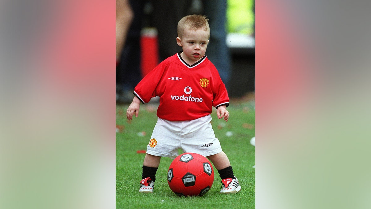 Brooklyn Beckham standing over a soccer ball while wearing a jersey in 2001.