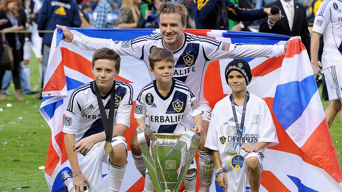 Brooklyn Beckham posing with his brothers and his dad at the Home Depot Center in December 2012.