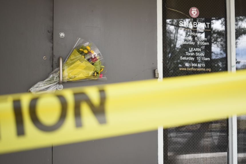 Caution tape and flowers cover the entrance to the Beth Israel Congregation.
