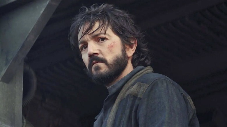 Diego Luna as bearded Cassian Andor frowning in a doorway in Andor