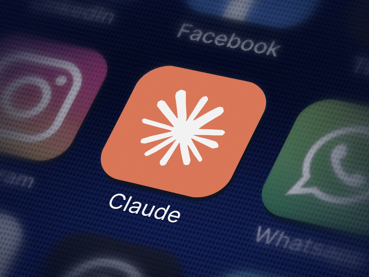 The Claude app – an orange background with a white Claude logo – on a smartphone screen.