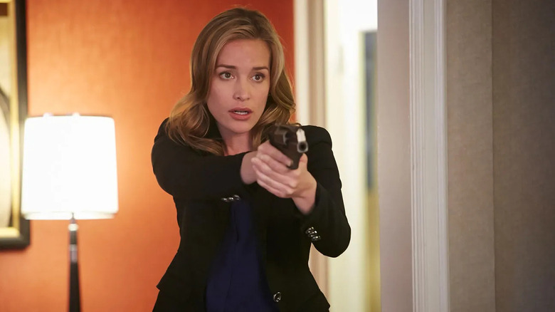 Annie Walker (Piper Perabo) aims a pistol by a lamp in Covert Affairs