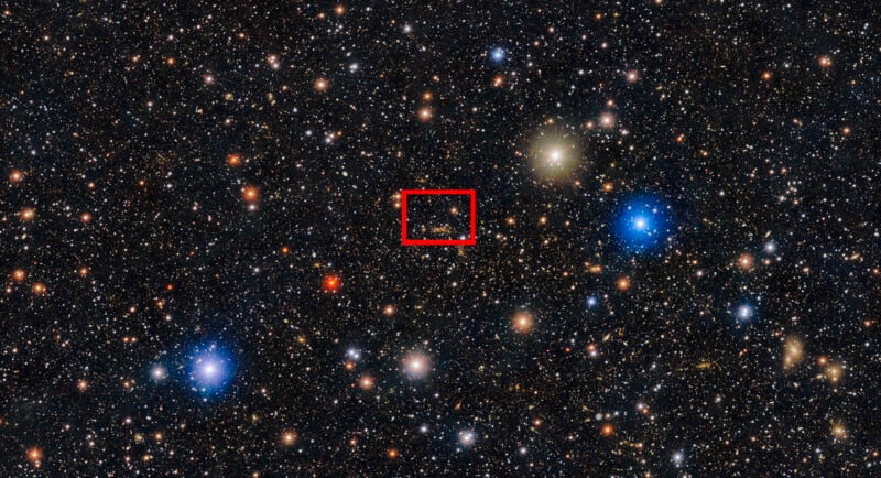 A dense star field in space with various colored stars and galaxies; a red rectangle highlights a specific cluster of faint stars near the center.