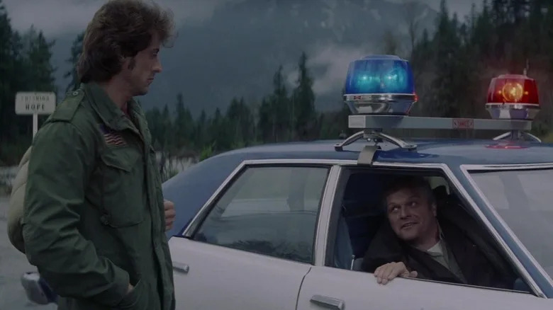 Sylvester Stallone's John Rambo stands on a street talking to Brian Dennehy's Sheriff William Teasle in First Blood