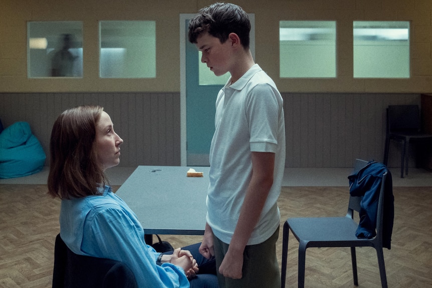 A tween boy towers over his psychologist as an intimidation tactic in the series Adolescence. 