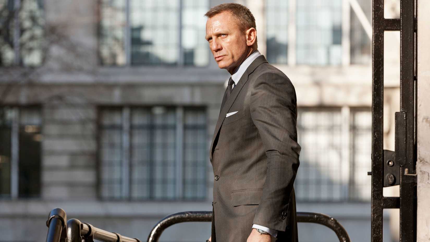 Daniel Craig stands in the street looking grimly determined in a scene from Skyfall