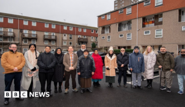 A group of 14 people standing on freshly laid parking spaces
