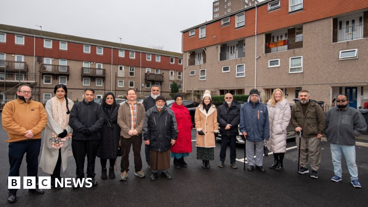 A group of 14 people standing on freshly laid parking spaces