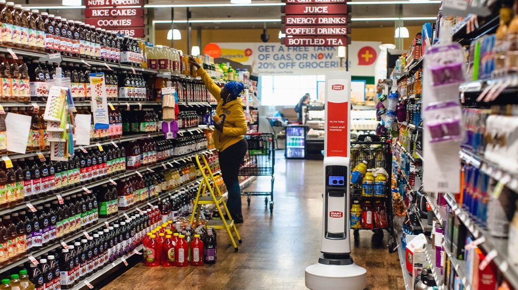 The beverages and drinks aisles in a supermarket as a person reaches for an item on the top shelf